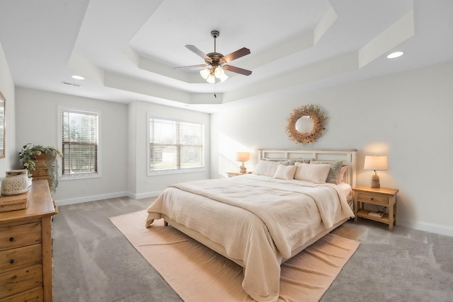 bedroom with a raised ceiling, baseboards, and light carpet