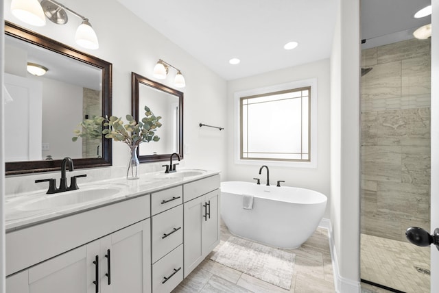 bathroom featuring double vanity, a stall shower, and a sink