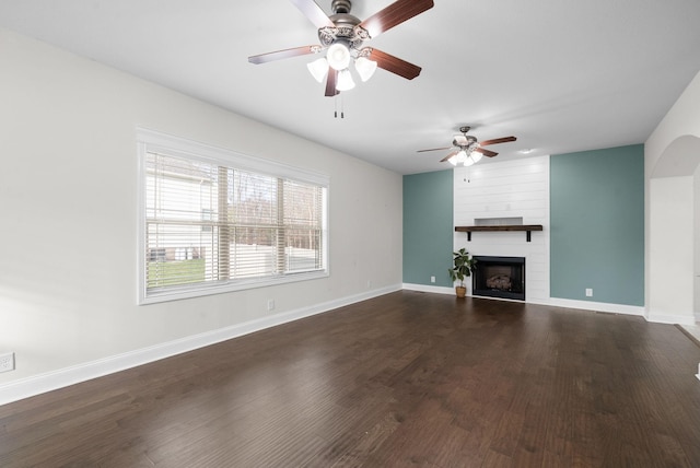 unfurnished living room featuring a fireplace, baseboards, and wood finished floors