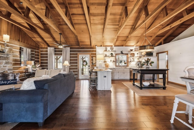 living room with vaulted ceiling with beams, ceiling fan, dark wood finished floors, wood walls, and wood ceiling
