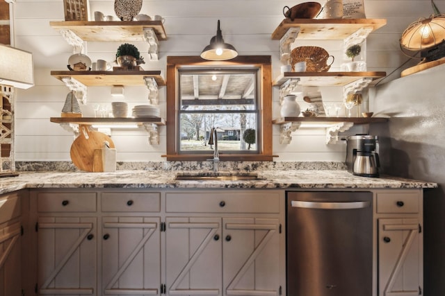 kitchen featuring stainless steel dishwasher, open shelves, light stone countertops, and a sink