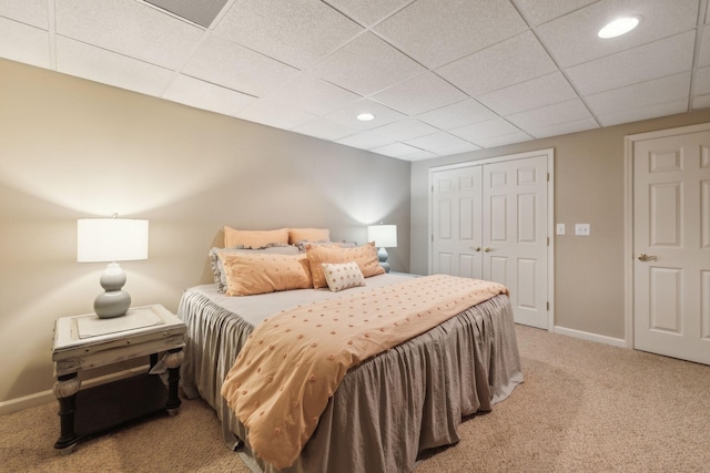 bedroom featuring a paneled ceiling, baseboards, a closet, and light carpet