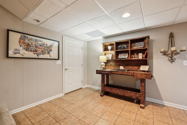 interior space featuring light tile patterned flooring, a paneled ceiling, and baseboards