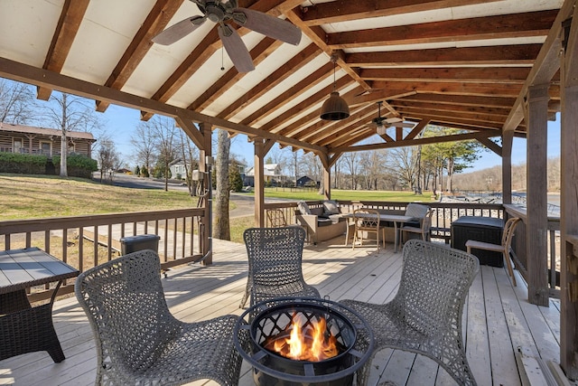 wooden terrace with a yard, a fire pit, and a ceiling fan
