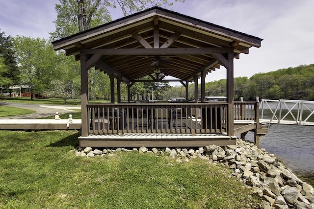 view of property's community featuring a gazebo, a lawn, and a deck with water view
