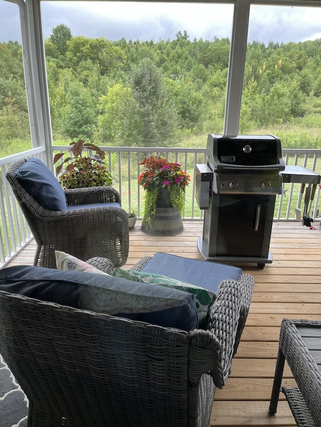 wooden deck featuring area for grilling and a wooded view