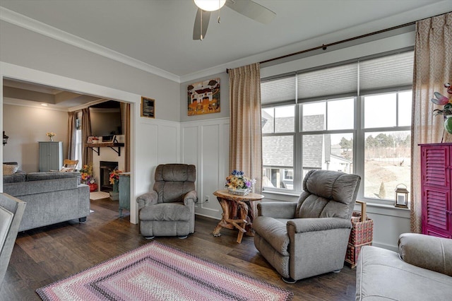 living area with a fireplace, wood finished floors, and ornamental molding