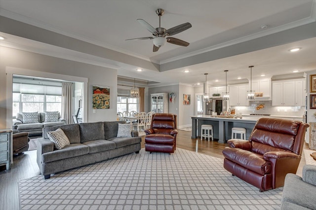 living area featuring recessed lighting, crown molding, a tray ceiling, and wood finished floors