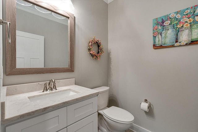 half bathroom with baseboards, toilet, and vanity