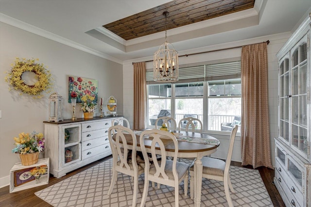 dining room featuring a tray ceiling, a notable chandelier, dark wood-style floors, and ornamental molding