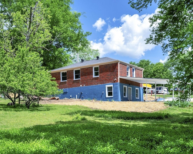 rear view of property with brick siding, a yard, and a carport