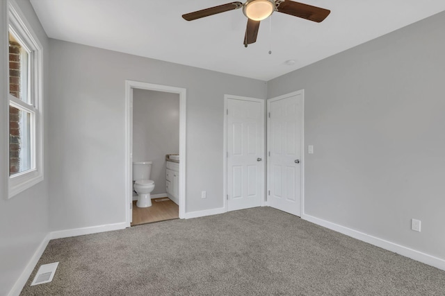 unfurnished bedroom featuring visible vents, baseboards, carpet floors, ensuite bathroom, and a ceiling fan