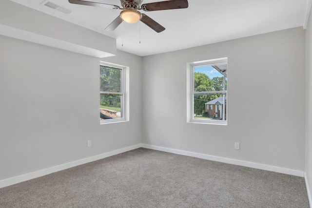 carpeted spare room with visible vents, a healthy amount of sunlight, and baseboards