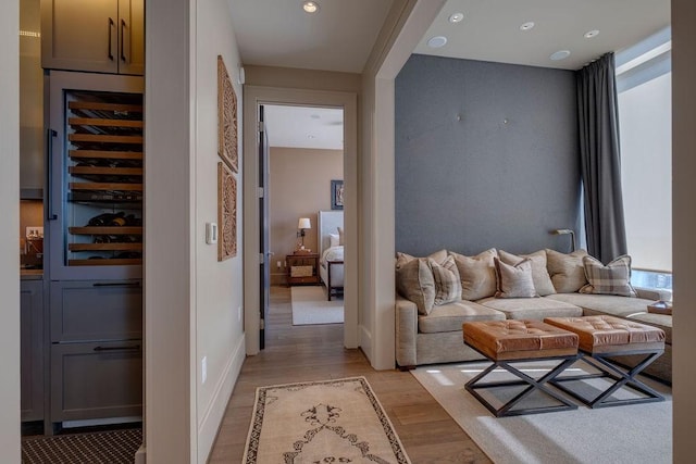 interior space with beverage cooler, recessed lighting, light wood-type flooring, and baseboards