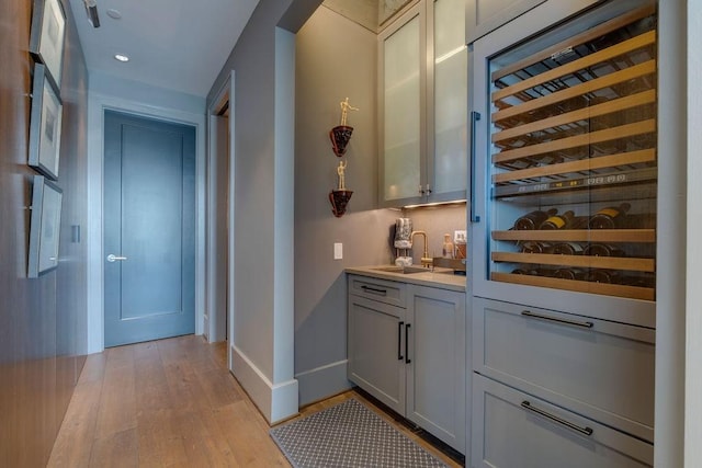 bar featuring recessed lighting, light wood-style flooring, baseboards, and a sink