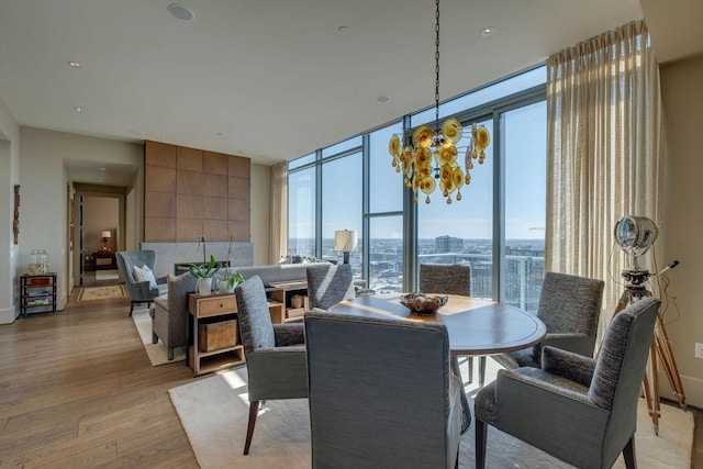 dining space with expansive windows, an inviting chandelier, and light wood finished floors