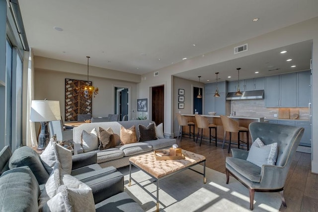 living room featuring an inviting chandelier, recessed lighting, wood finished floors, and visible vents