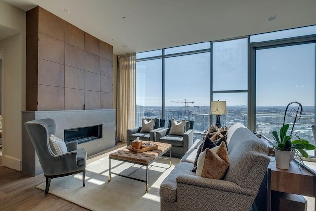 living area featuring a fireplace, a wall of windows, and wood finished floors