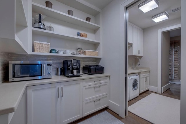 interior space featuring a sink, dark wood-style floors, baseboards, washer / dryer, and laundry area