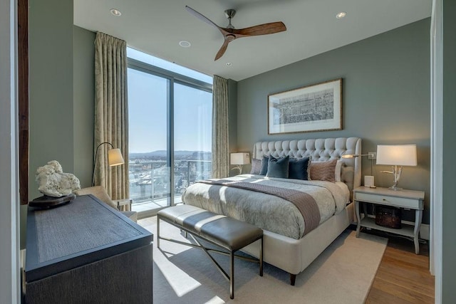 bedroom featuring access to exterior, ceiling fan, expansive windows, recessed lighting, and wood finished floors