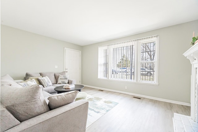 living room featuring visible vents, baseboards, and light wood finished floors