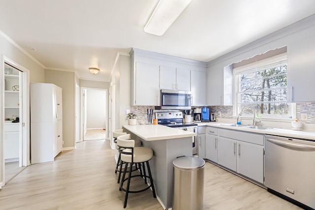 kitchen with a sink, decorative backsplash, a breakfast bar area, and stainless steel appliances