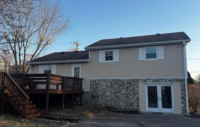 rear view of house with stone siding, french doors, stairs, and a deck