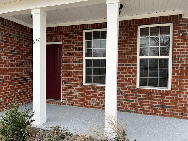 doorway to property with brick siding and covered porch