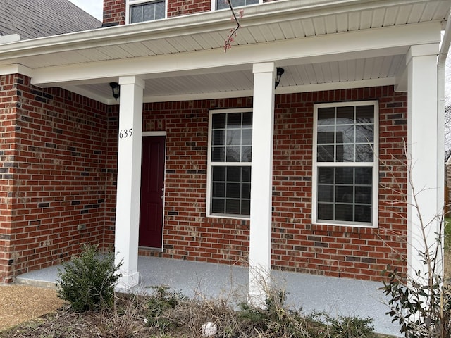 view of exterior entry with a porch and roof with shingles