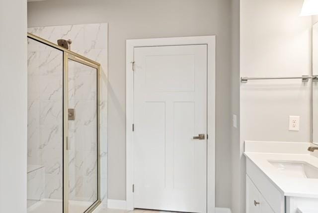 bathroom featuring a marble finish shower, vanity, and baseboards