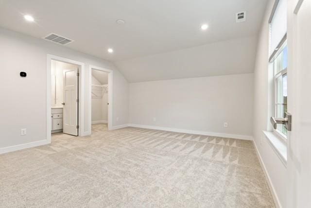 additional living space with light carpet, visible vents, lofted ceiling, and baseboards