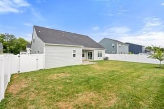 rear view of property featuring a fenced backyard and a yard