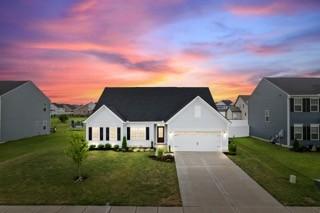 view of front of house with an attached garage, concrete driveway, and a front yard