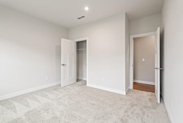 unfurnished bedroom with visible vents, baseboards, and light colored carpet