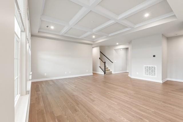 unfurnished room with baseboards, visible vents, coffered ceiling, light wood-style flooring, and stairs