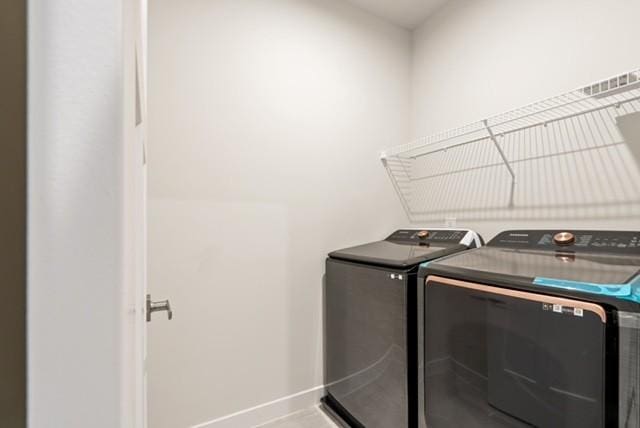 washroom with laundry area, washer and dryer, and baseboards