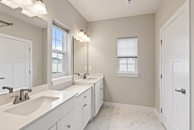 bathroom featuring vanity, a healthy amount of sunlight, marble finish floor, and baseboards