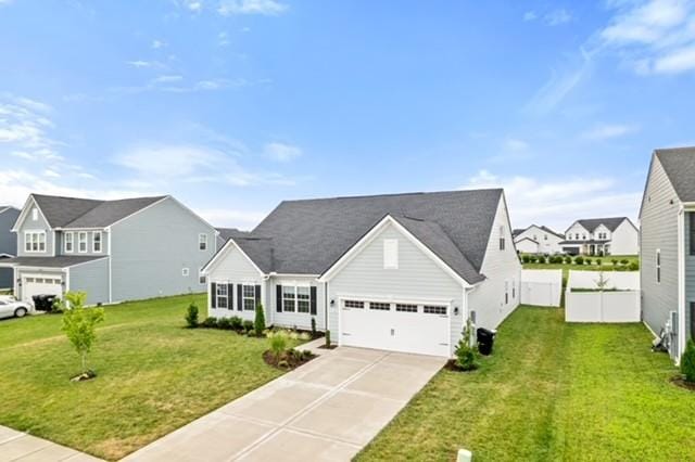 view of front of property with a front lawn, driveway, fence, a residential view, and a garage