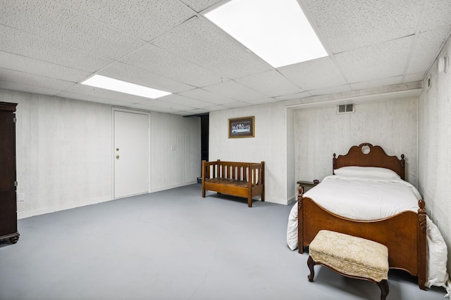 bedroom with visible vents, concrete flooring, and a paneled ceiling