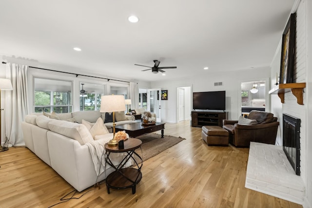 living area featuring a wealth of natural light, light wood-type flooring, and a ceiling fan