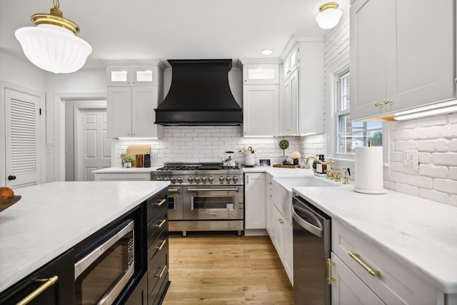 kitchen featuring premium range hood, stainless steel appliances, white cabinets, and a sink