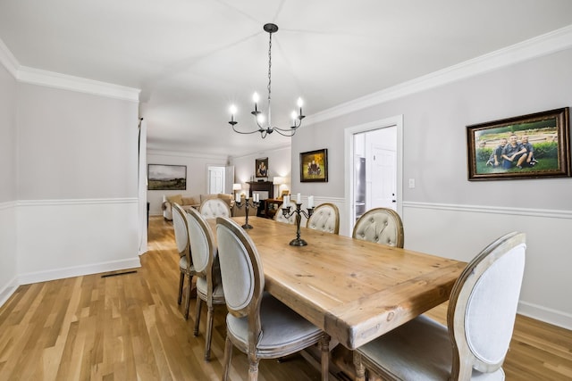 dining room featuring an inviting chandelier, baseboards, crown molding, and light wood-style floors