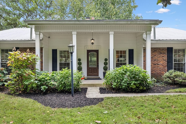 view of exterior entry featuring brick siding and metal roof