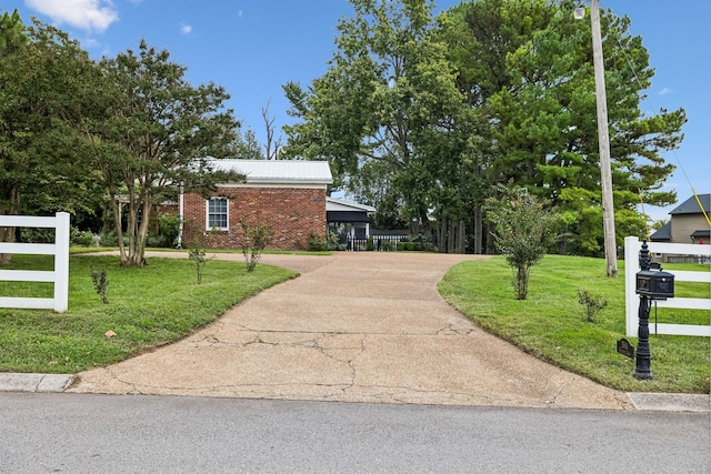 view of front of property featuring a front yard, fence, brick siding, and driveway