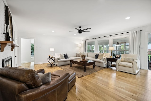 living area with a ceiling fan, baseboards, a fireplace, recessed lighting, and light wood-style floors