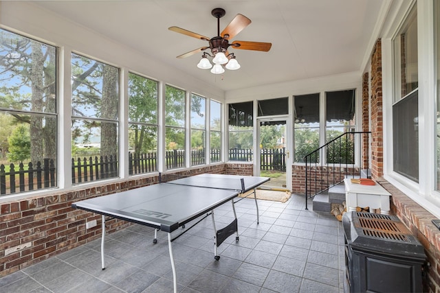 playroom featuring ceiling fan and brick wall