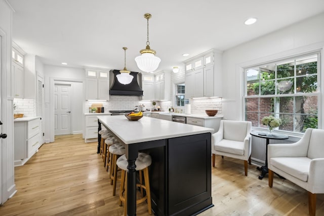 kitchen featuring a kitchen island, light countertops, light wood-style flooring, custom exhaust hood, and white cabinets