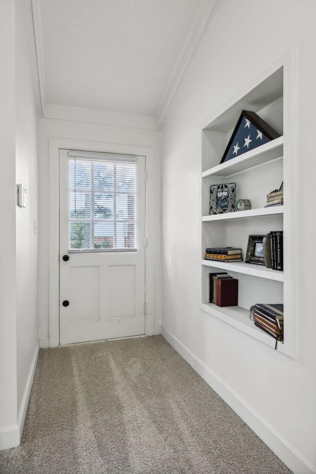 doorway featuring baseboards, carpet floors, built in shelves, and crown molding