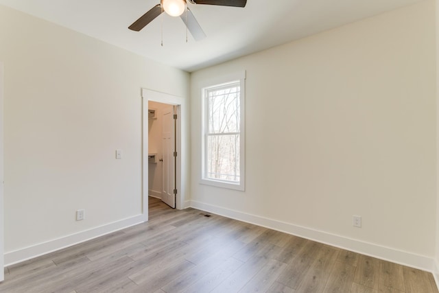 spare room featuring a ceiling fan, visible vents, baseboards, and light wood-type flooring