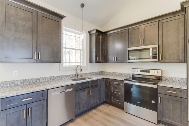 kitchen featuring light wood-style flooring, a sink, stainless steel appliances, vaulted ceiling, and dark brown cabinetry